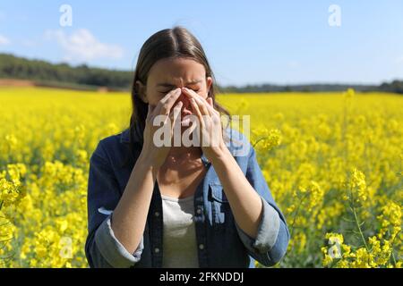 Femme allergique se grattant les yeux qui démangent au printemps en a champ à fleurs jaunes Banque D'Images