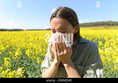 Femme souffrant d'allergie toux dans un champ fleuri jaune dans saison de printemps Banque D'Images