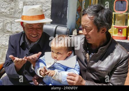 (210503) -- LHASSA, le 3 mai 2021 (Xinhua) -- Dondrup Wangyal (1er L) interagit avec son arrière-petit-fils dans le canton de Gangdoi, comté de Gonggar de la ville de Shannan, région autonome du Tibet du sud-ouest de la Chine, le 5 avril 2021. Dondrup Wangyal, 79 ans, est né d'une famille de sérans dans le canton de Gangdoi. Pendant des générations, la famille de Dondrup Wangyal avait été serfs d'une famille de seigneur local jusqu'à la réforme démocratique en 1959 quand il était vraiment émancipé et affecté avec des terres agricoles. "J'avais seulement 17 alors, mais je n'oublierais jamais le fait que le Parti communiste de Chine m'a sauvé. Et j'ai décidé de devenir membre du Parti Banque D'Images