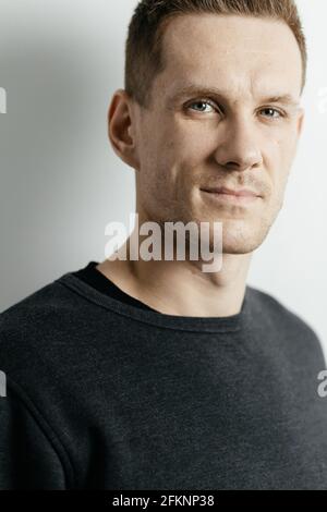 Portrait en gros plan d'un jeune homme aux cheveux rouges qui regarde l'appareil photo sur l'arrière-plan d'un mur gris. Place pour votre texte. Banque D'Images