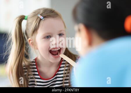 Otorhinolaryngologiste médecin examinant mal de gorge petite fille en clinique Banque D'Images