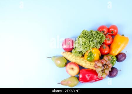 Concept de saines habitudes alimentaires propres. Fruits, légumes et légumes verts se mélangent sur fond blanc bleu. Poivre, tomate, laitue, épis de maïs, poire et pomme, prune Banque D'Images