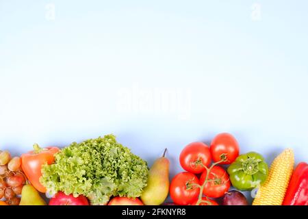 Concept de saines habitudes alimentaires propres. Fruits, légumes et légumes verts se mélangent sur fond blanc bleu. Poivre, tomate, laitue, épis de maïs, poire et pomme, prune Banque D'Images