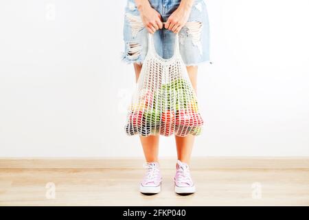 Jeune femme en chemise à carreaux, jupe jeans avec sac de fruits, légumes et légumes verts : épis de maïs, tomate, poivre, laitue, poire et pomme. Aucune conc. De déchets Banque D'Images