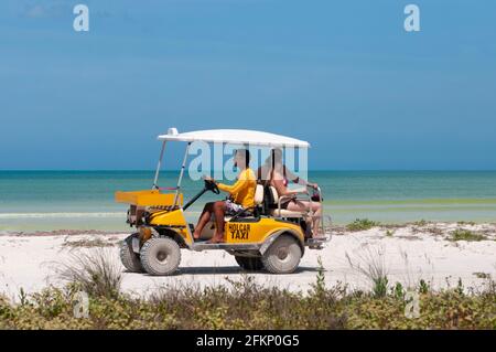 Un taxi de voiture de golf jaune sur une plage tropicale sur l'île de Holbox au Mexique, transportant des touristes. Dans le fond de la mer des Caraïbes, et le blues Banque D'Images