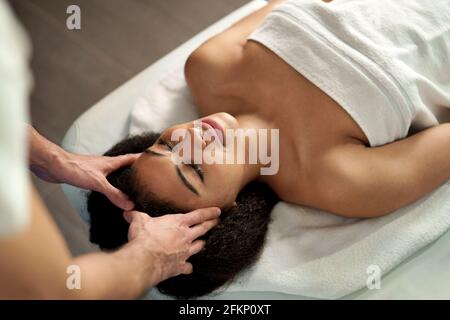 Vue de dessus de la jeune femme ayant un massage de la tête au spa. Banque D'Images