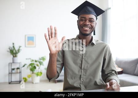 Portrait de jeune homme afro-américain portant une casquette de remise de diplômes et en agitant l'appareil photo à l'intérieur de la maison, dans l'espace de copie Banque D'Images