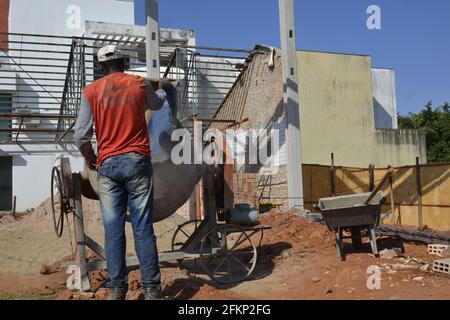 Homme travaillant. Ouvrier versant le sac de ciment dans le mélangeur de béton pour la construction au Brésil, en Amérique du Sud Banque D'Images