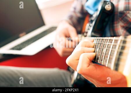 Jeune homme, chanteur de folk hippster auteur-compositeur en chemise à carreaux, jouant de la guitare électrique offset Sunburst. Guitariste mâle prenant de la musique jazz en ligne c Banque D'Images