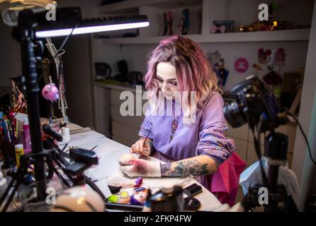 Strasburg, Allemagne. 29 avril 2021. La couturier Elisa Lange peint la poupée manga 'Lylla' qu'elle a conçue dans l'atelier. L'homme de 32 ans diffuse son travail sur Internet et fournit maintenant des clients partout dans le monde. Elle a déjà remporté des fans aux États-Unis, au Japon et au Canada avec sa poupée de bal et de socket 'Lylla'. Les fans de poupées peuvent suivre la création de poupées et de vêtements sur sa chaîne YouTube. Credit: Jens Büttner/dpa-Zentralbild/ZB/dpa/Alay Live News Banque D'Images