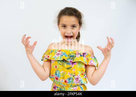 Petite fille hispanique folle et folle criant et hurlant avec les bras levés. Concept de frustration. Banque D'Images