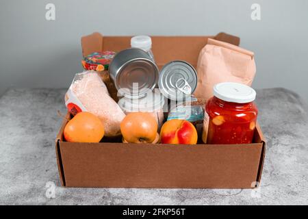 Boîte de dons avec divers aliments. Ouvrir la boîte en carton contenant de l'huile, des légumes, du lait, des conserves, des céréales et des pâtes. Concept de livraison de nourriture avec espace pour Banque D'Images