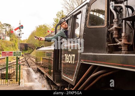 Un chauffeur de train à vapeur signale qu'il est prêt à partir sur la ligne Watercress, Mid Hants Railway, un chemin de fer à vapeur historique, Alresford, Hampshire, Royaume-Uni Banque D'Images