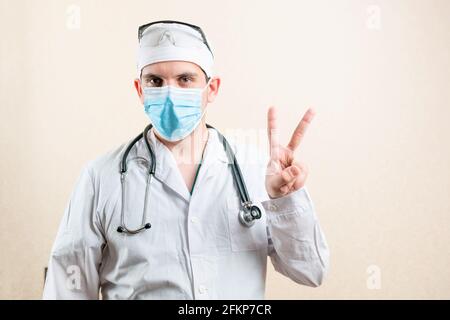 Le médecin dans le masque et les lunettes montre deux doigts. Photo de haute qualité Banque D'Images