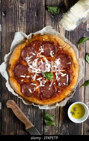 Pizza au pepperoni sur fond de bois. Pizza coupée en tranches et cheesy ...