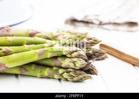 Asperges vertes non cuites fraîches sur table blanche. Banque D'Images