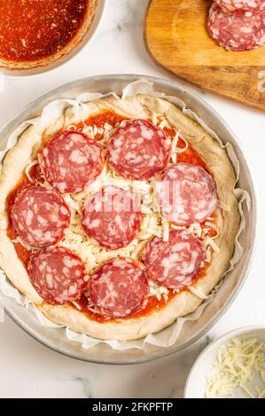 Pizza au pepperoni : pâte à pizza dans une casserole avec sauce tomate, fromage mozzarella et salami rouge italien sur le dessus Banque D'Images