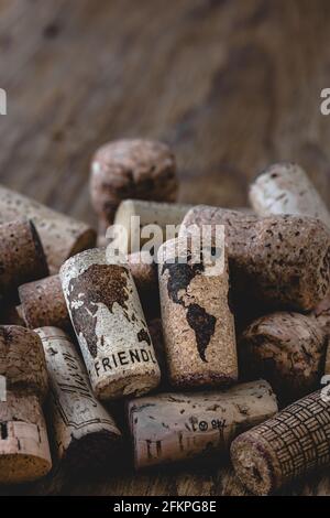 Deux corks sur une pile de corks utilisés qui montrent une carte du monde et le mot amical. Arrière-plan vieux bois. Concept du monde meilleur. Banque D'Images