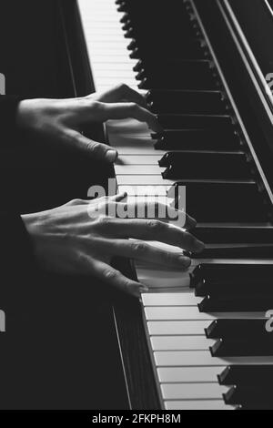 Deux mains sur un clavier de piano, photo verticale en noir et blanc Banque D'Images