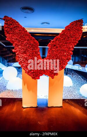 Grandes ailes de roses rouges sur un piédestal, lampes rondes blanches en arrière-plan Banque D'Images