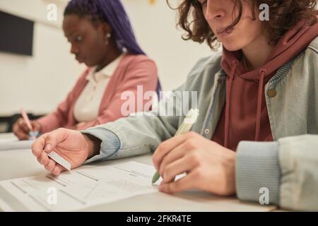 Portrait rogné d'un étudiant qui lit une note de triche tout en prenant l'examen à l'école, espace de copie Banque D'Images