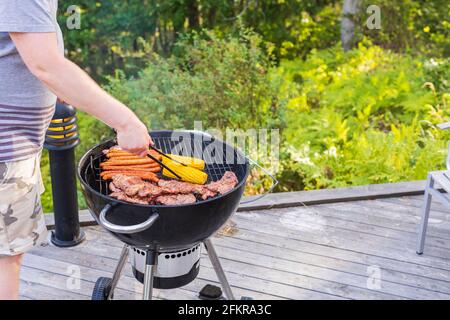 Vue rapprochée des mains de l'homme qui grillent des aliments sur un gril à charbon. Suède. Banque D'Images