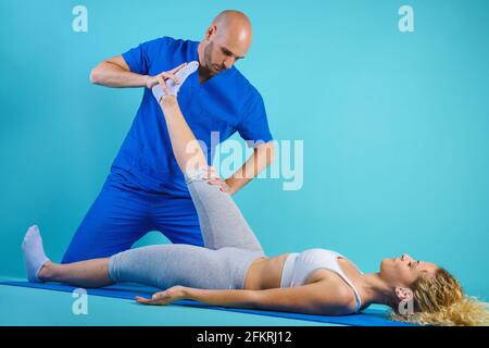 Fille effectue des exercices avec un physiothérapeute. Fond cyan Banque D'Images