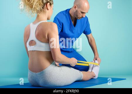 Fille effectue des exercices avec un physiothérapeute. Fond cyan Banque D'Images