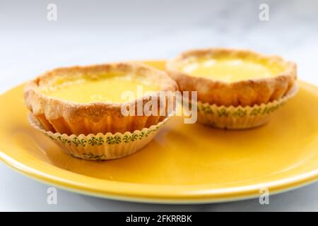 Un gros plan de tartes d'œufs sur une assiette jaune. Banque D'Images