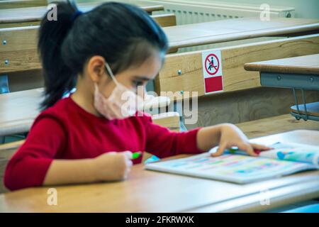 Image concentrée sur ne pas s'asseoir ici étiquette derrière la fille étudier dans une salle de classe vide avec un masque de protection Banque D'Images