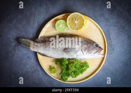 Poisson-mérou sur une assiette en bois, poisson frais de fruits de mer crus pour les aliments cuits Banque D'Images