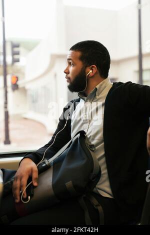 Jeune homme voyageant en train léger wearing earphones Banque D'Images