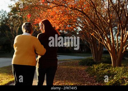 Vue arrière d'une femme âgée et d'une fille adulte se promenant dans le parc de banlieue Banque D'Images