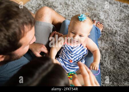 High angle view of mid adult couple jouant avec sa petite fille sur les genoux Banque D'Images