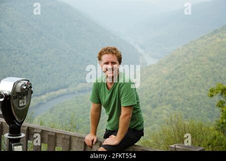 Portrait of mid adult man sitting on plate-forme panoramique, New River Gorge River National, Fayetteville, West Virginia, USA Banque D'Images