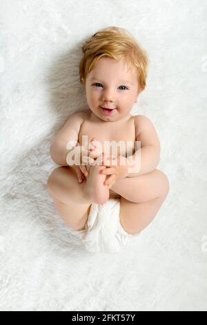 Toddler lying on blanket, holding pieds, smiling Banque D'Images