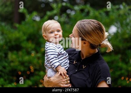 Mother holding baby girl, outdoors, smiling Banque D'Images