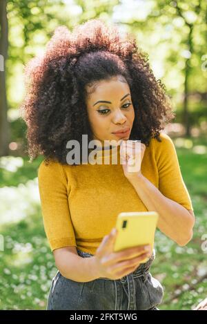 Jolie femme afro bavarde dans un jardin, très surpris. Banque D'Images