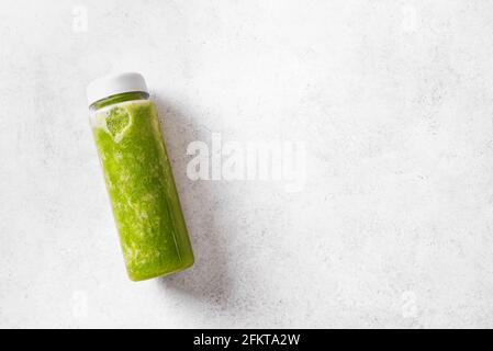 Smoothie vert dans une bouteille en plastique sur fond blanc, vue du dessus, espace de copie. Smoothie frais de détox cru ou jus de vert pour une alimentation saine. Banque D'Images