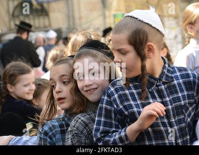 Des enfants orthodoxes juifs attendent en file pour de la nourriture et des bonbons servis par un homme juif juste pendant les préparatifs de la Pâque à MEA She'arim Jérusalem. Banque D'Images