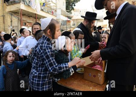 Des enfants orthodoxes juifs attendent en file pour de la nourriture et des bonbons servis par un homme juif juste pendant les préparatifs de la Pâque à MEA She'arim Jérusalem. Banque D'Images