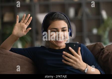 Gros plan femme indienne dans un casque, en agitant la main, à l'aide d'un smartphone Banque D'Images