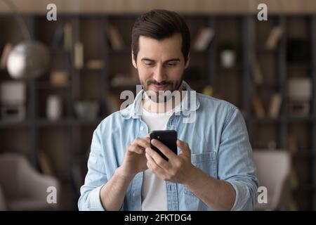 Gros plan homme satisfait utilisant le téléphone, regardant l'écran Banque D'Images