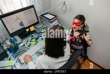 Femme travaillant de la maison avec sa fille l'interrompant Banque D'Images