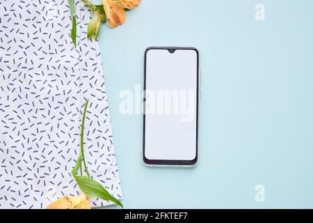 Écran du téléphone pour le texte sur fond bleu. Concept de printemps avec fleurs d'alstroemeria. Photo de haute qualité Banque D'Images