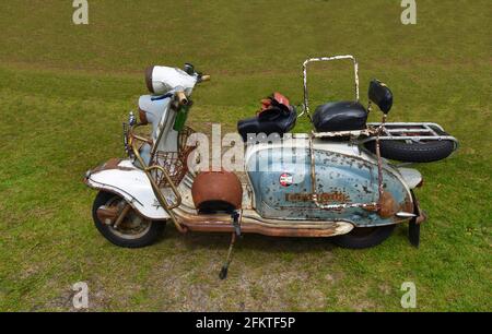 Scooter à moteur Lambretta bleu et blanc très rouillé avec casque et gants rouillés. Banque D'Images