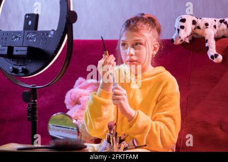Une adolescente montre à l'appareil photo une brosse pour les cils. L'adolescent peint les cils. Cosmétiques pour les cils. Banque D'Images