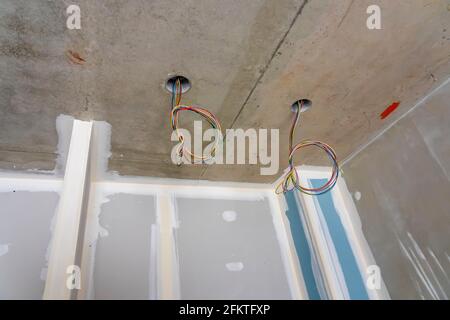 Intérieur d'un nouvel appartement en construction sans finition dans des tons sombres avec trous électriques et câblage pour projecteur de plafond. PH de haute qualité Banque D'Images