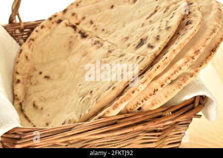 Plusieurs pain pita fraîchement cuit avec un panier de vigne, gros plan, sur une table en bois. Banque D'Images