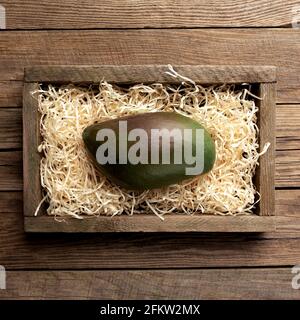 Fruits frais de mangue tropicale dans une boîte de livraison en bois sur fond de bois. Concept de saine alimentation vue de dessus plat avec espace de copie pour quelques annonces Banque D'Images